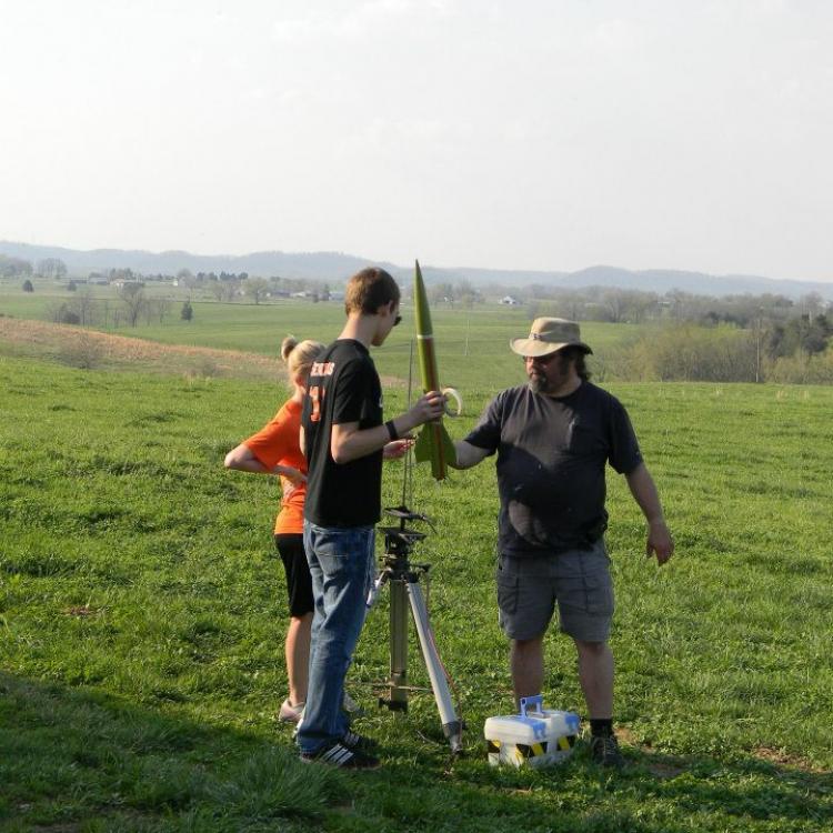  Three people holding model rocket 